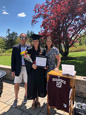 A student celebrating graduation at home with her family