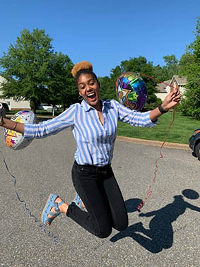 A graduate jumping for joy at home