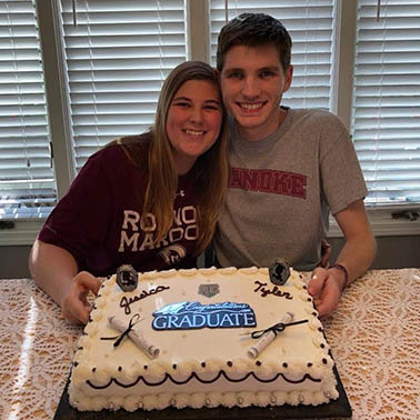 Graduates posing with a cake from their family