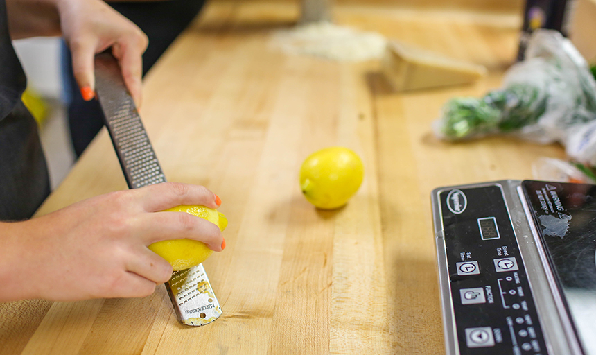 Hand zesting lemon on countertop