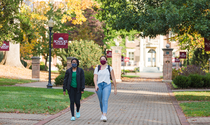 Two students walking on campus wearing face coverings