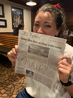 A student holding up her mock diploma at a restaurant after the ceremony