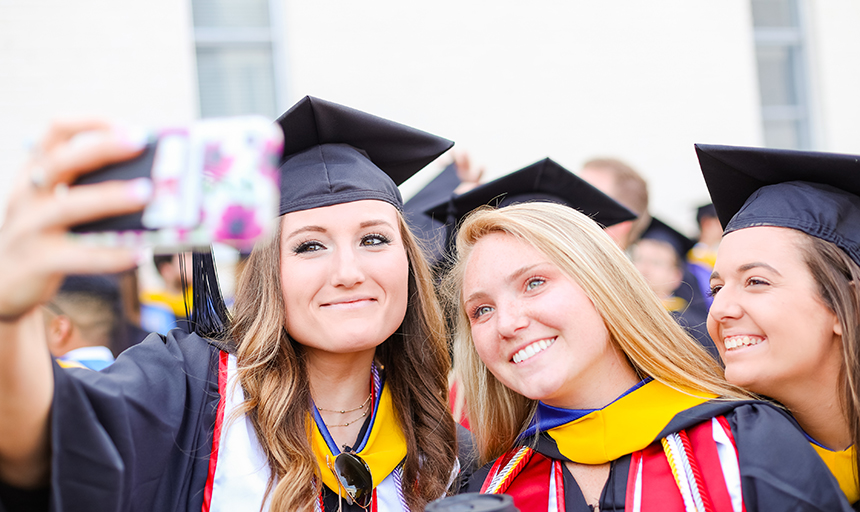 Students take selfie in caps and gowns