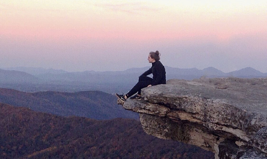 student on mountain at sunset