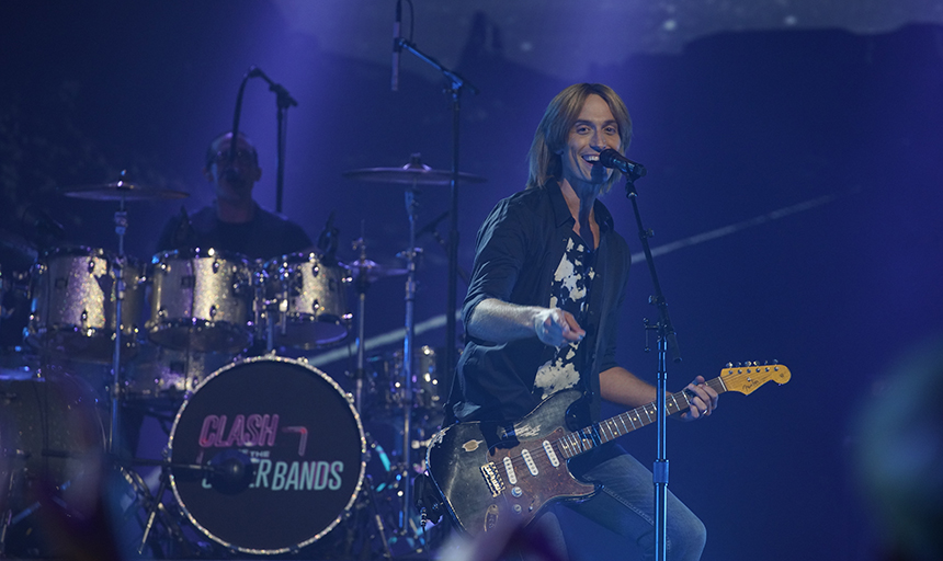 Man on stage smiling with guitar