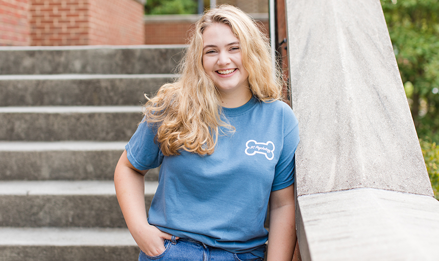 Student smiling outdoors in RC Psychology shirt