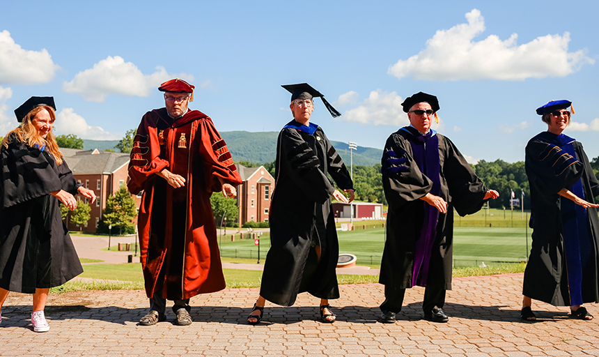 Five professors dance while dressed in academic robes