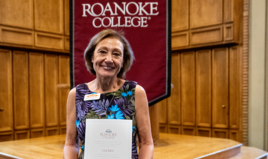 Lisa Bain stands before Roanoke College banner