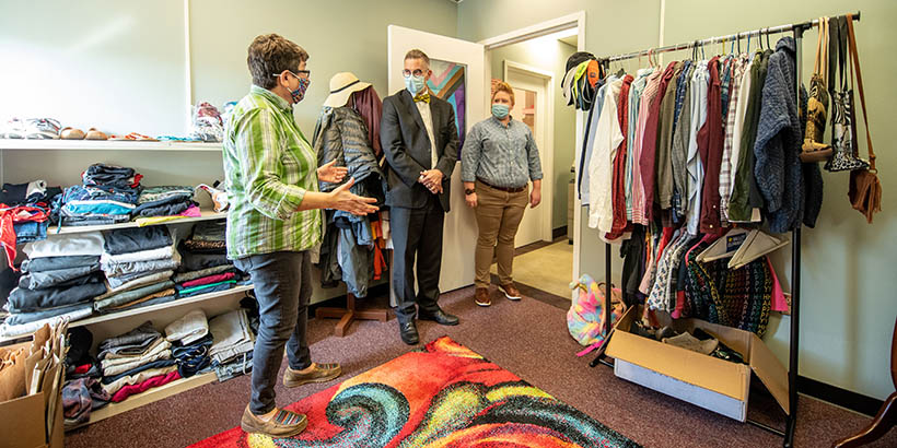 People in a room full of shelves of clothing and clothing on hangers