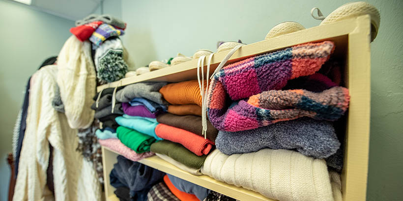 A closeup of a shelf full of clothing and hangers of clothing off to the side