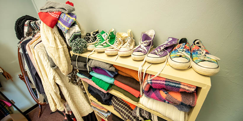 A closeup of a shelves full of clothing and hangers of clothing off to the side