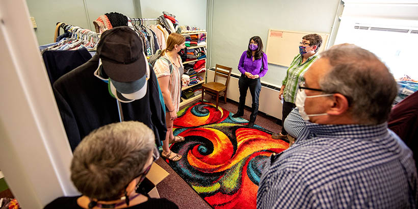 Several people in a room full of shelves of clothing and clothing on hangers