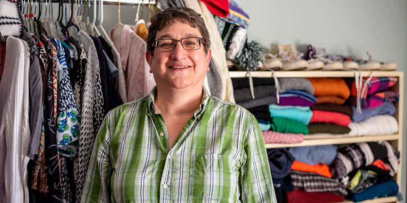 An employee smiling in front of racks and shelves full of clothing