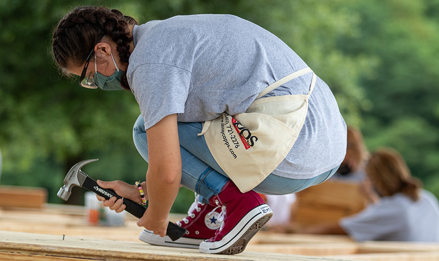 Student nails into the floor of a house under construction