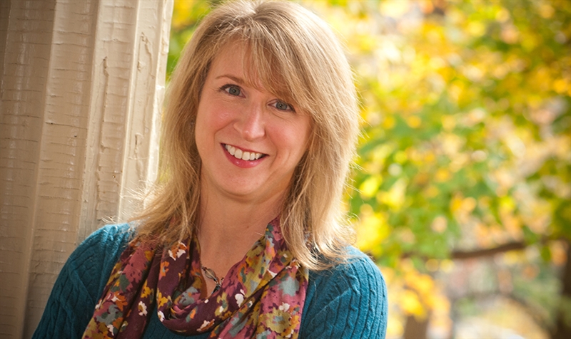 Sandee McGlaun with column beside her and leaves in the background