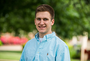 man smiling outdoors on campus