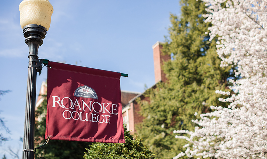 Roanoke College banner next to blooming tree