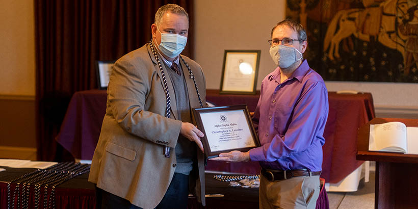 Faculty members holding up a framed certificate