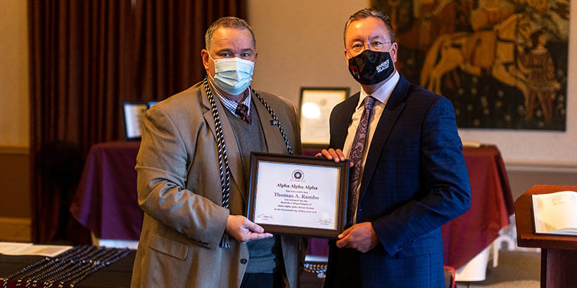 Faculty members holding up a framed certificate