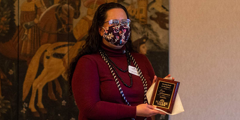 A faculty member holding up their plaque