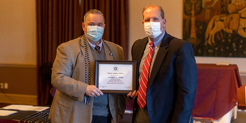 Two faculty members holding up a framed certificate