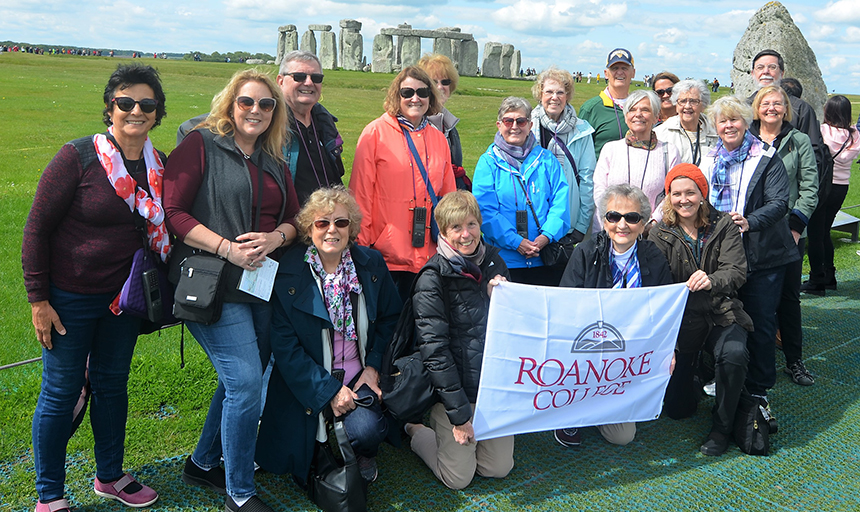 group of people at Stonehenge holding Roanoke College flag