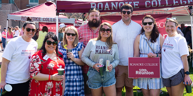Several people stand under a tent that says Roanoke College with 10th reunion sign