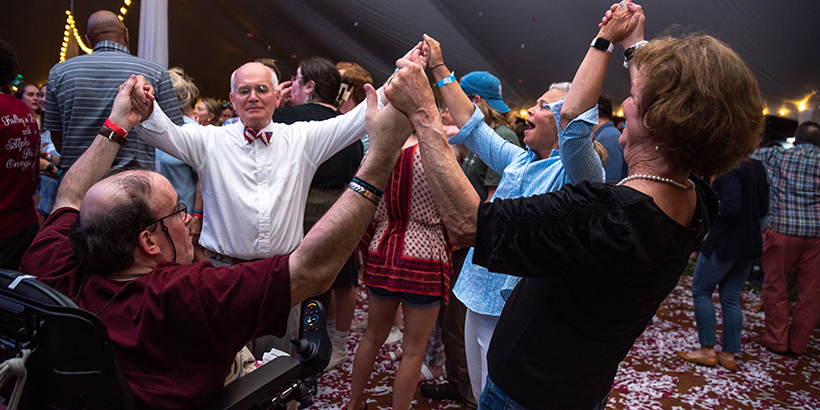 Four people holding hands up together as they are on the dance floor