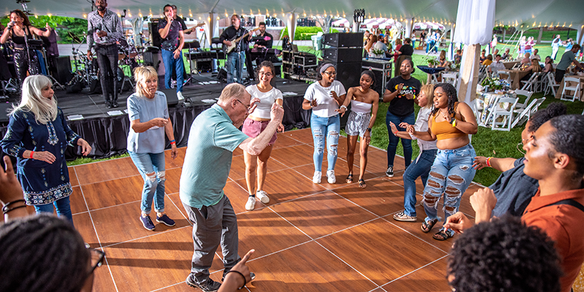 Man is in the  middle of a circle of people on the dance floor