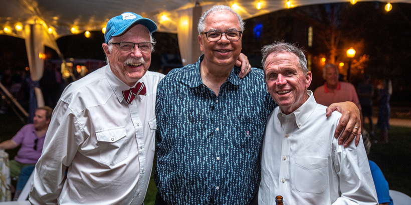 3 people stand together and smile for the camera