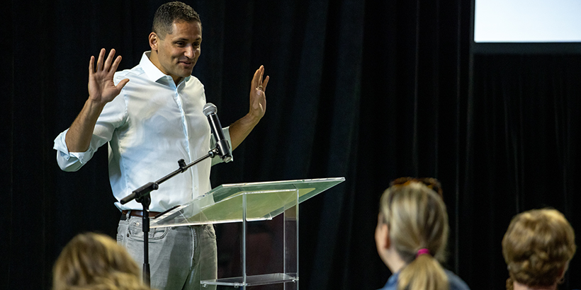 Man holds hands up while standing behind a podium