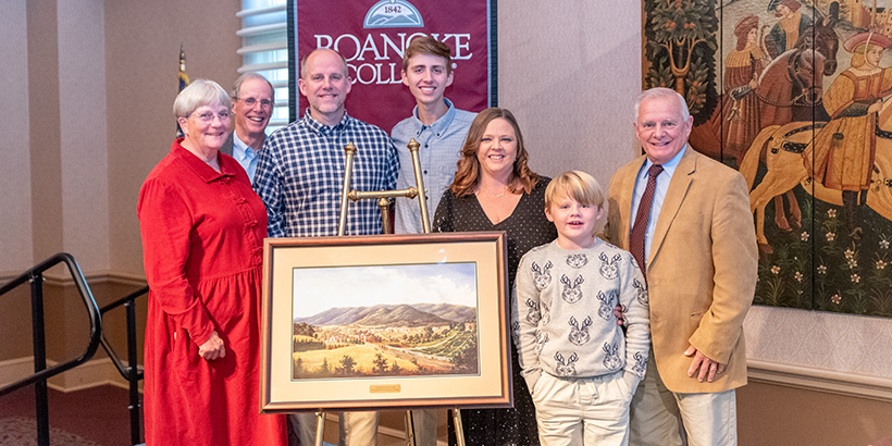 Two men, two women and two boys stand around a framed artwork