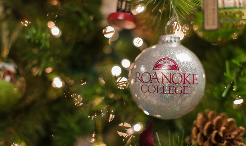 Roanoke College ornament on a lighted tree with other ornaments and a pine cone