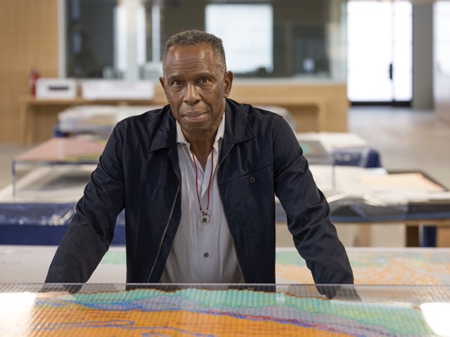 Man standing at table with artwork in front of him