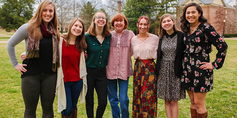 seven women standing arm in arm. 