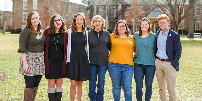 seven people standing arm in arm. 