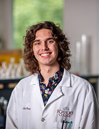Young man wearing lab coat with lab in background