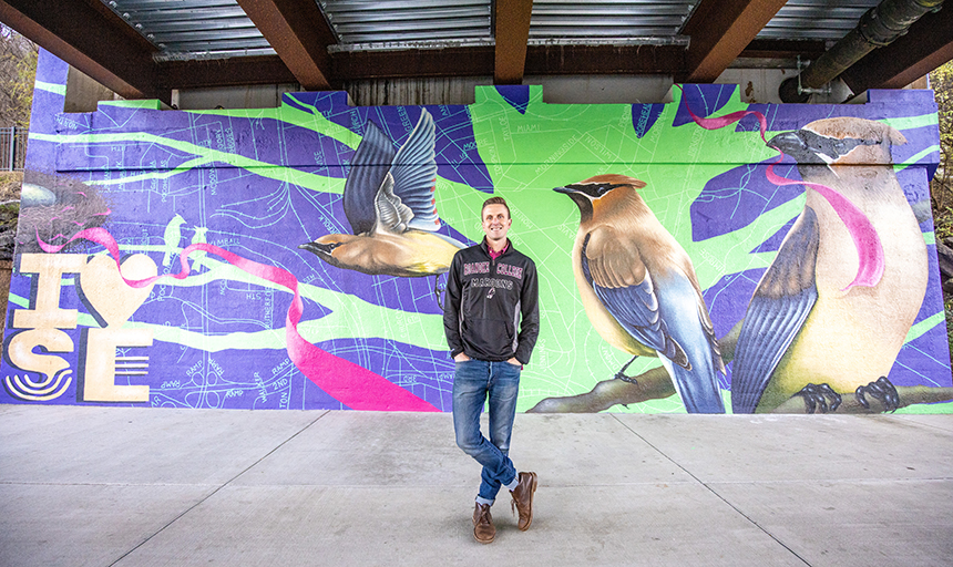 Jon Murrill '09 poses in front of his mural under the 9th Street bridge in Southeast Roanoke.