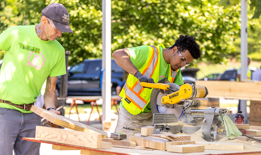 two young men work on construction site with electric saw