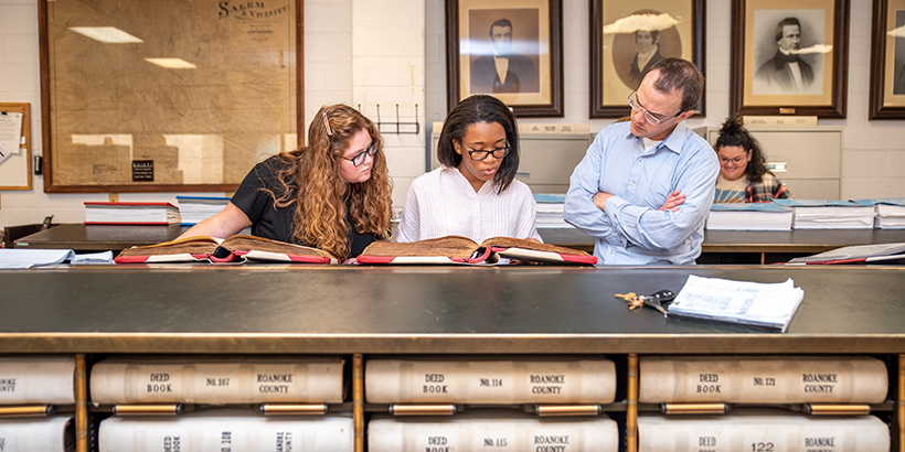 Two students go through handwritten record books