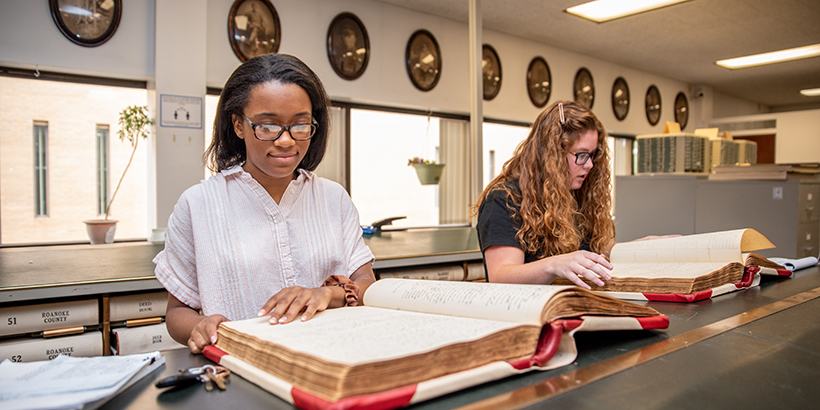 Two students go through handwritten record books