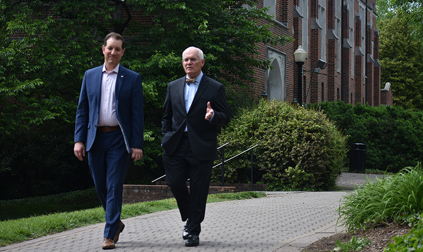 Two people in suits walk on the Roanoke College campus