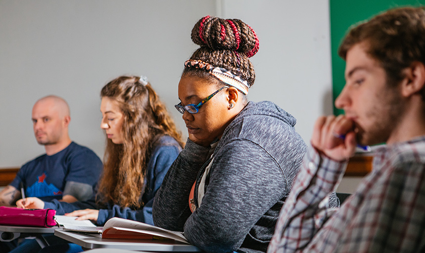 four students in classroom with books