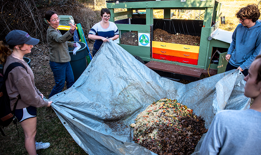 Students carry soil in tarp by multicolored trailer