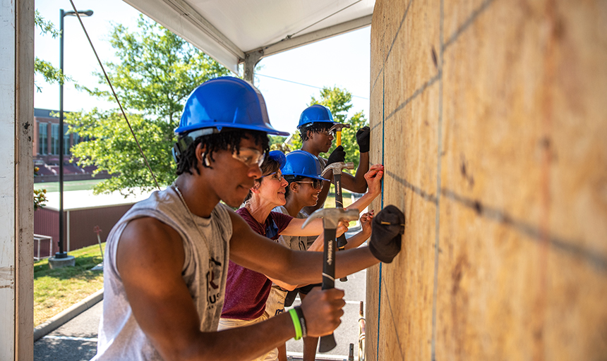 Kelly Shushok drives nails alongside students at R House Day in July.