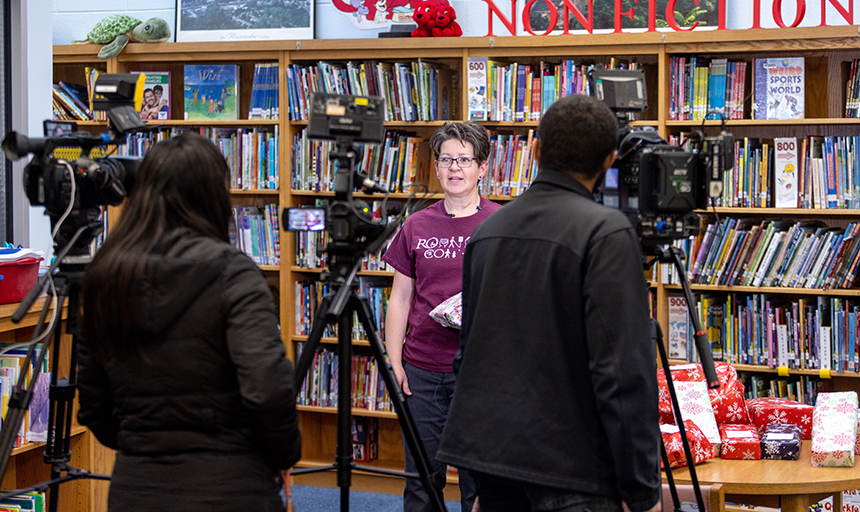 Professor is interviewed by two tv stations with books behind her