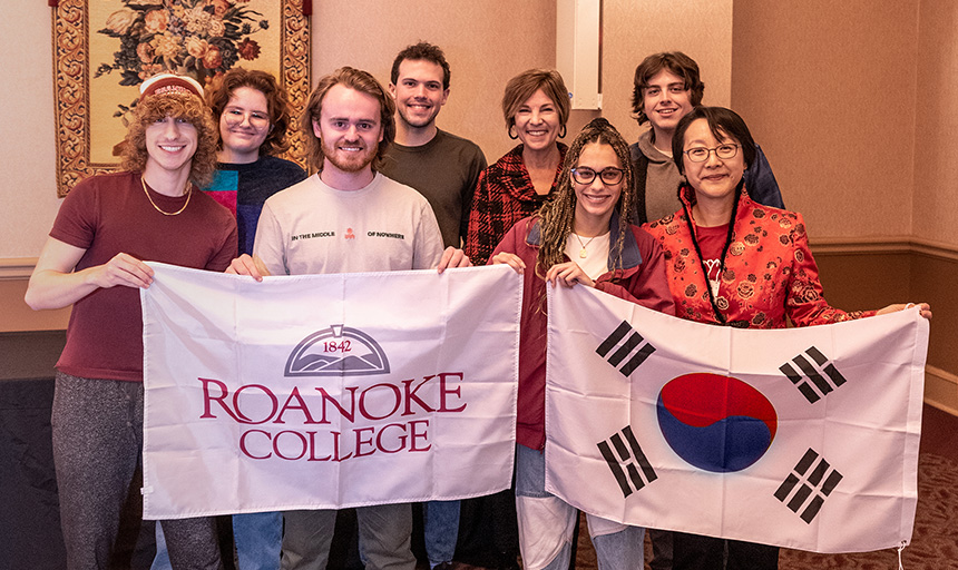 The student-faculty research team pose for a picture holding a Roanoke College flag and a South Korea flag