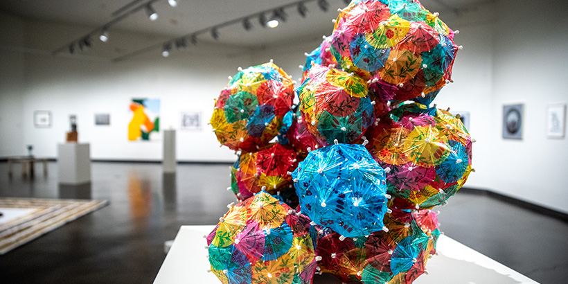A colorful artwork comprised of balls made up of items similar in appearance to cocktail umbrellas