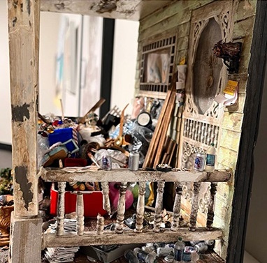 Close-up image of miniature diorama depicting a hoarder's porch crowded with garbage and other items