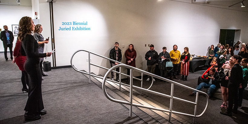 Organizers stand at the top of a small stairway to address exhibit visitors